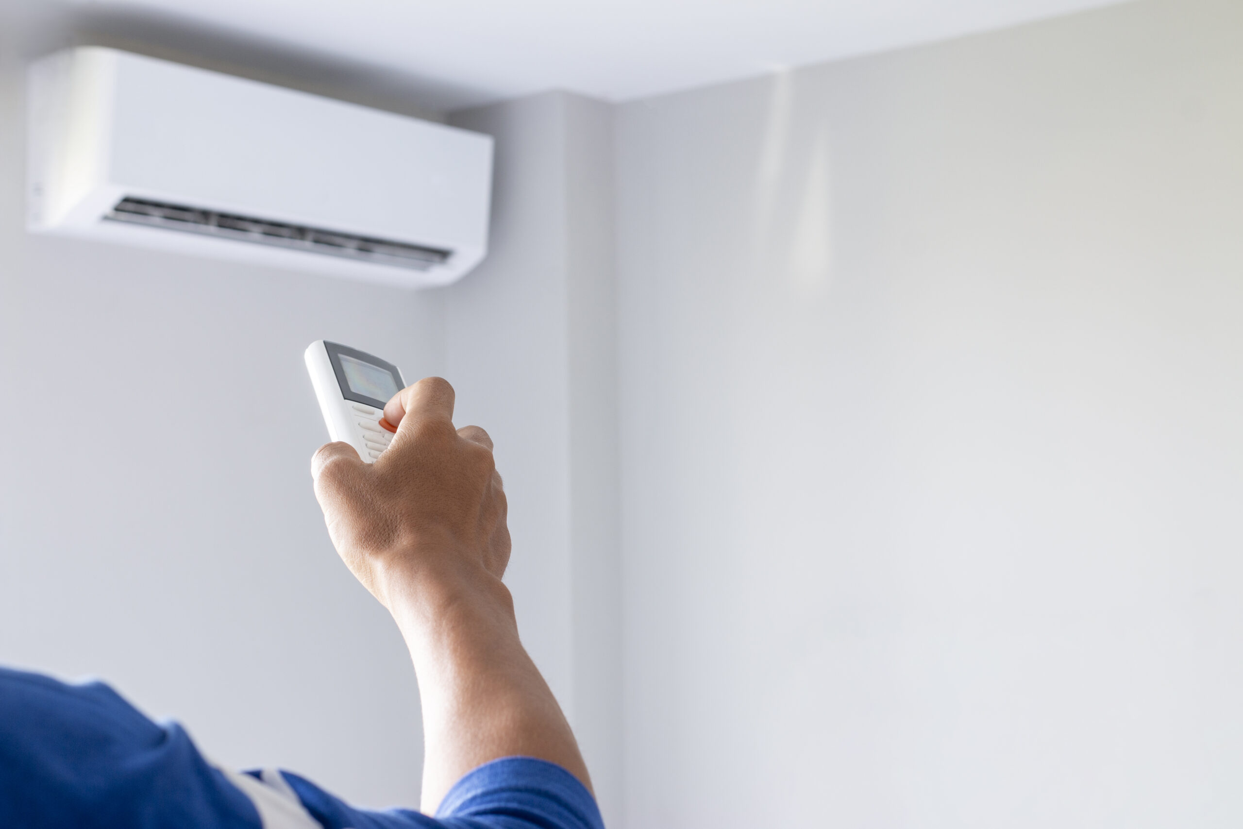 Close-up Of Man Hand Operating Air Conditioner With Remote Control.